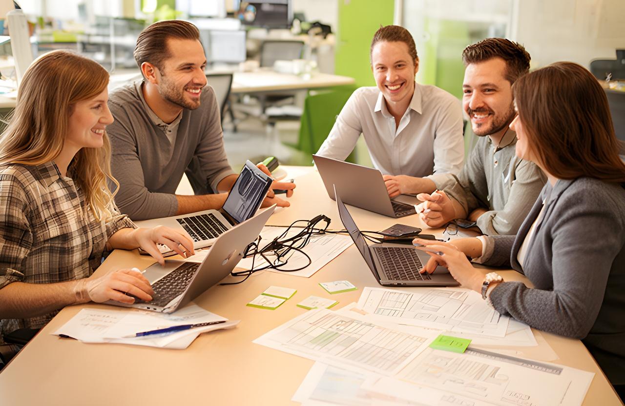 Friendly database team in a bright New Rochelle office reviewing project plans at a shared table