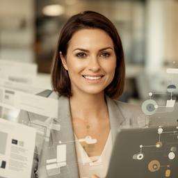 Mara Jensen smiling in a New Rochelle office beside a laptop and database diagrams